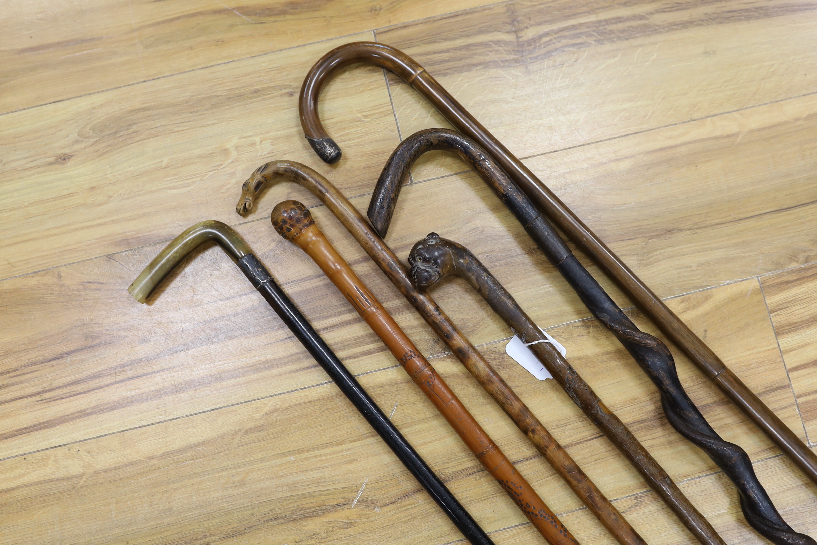 Six assorted walking sticks: a spiral carved cane, a silver mounted, a horn handled, a carved dog handled and a carved horse handled walking stick